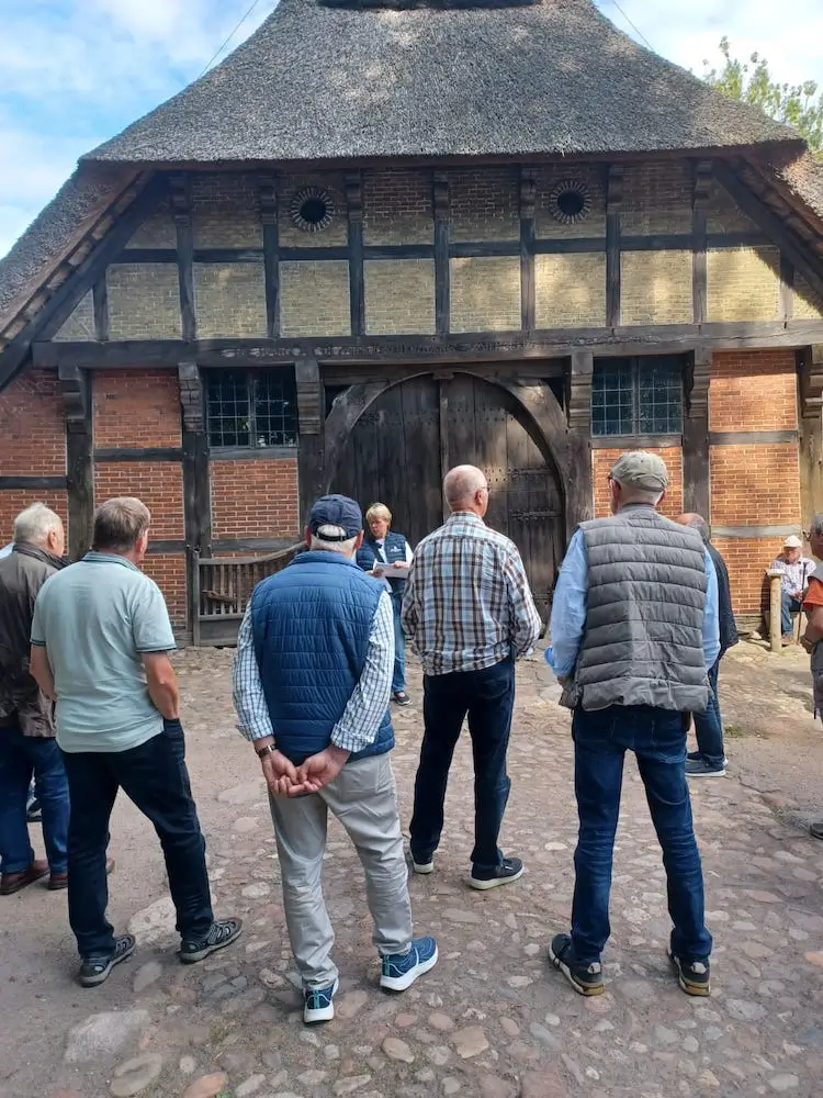 Eine Gruppe Männer steht außen vor einem alten Fachwerkhaus und bestaunt es.