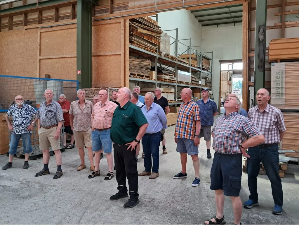 Eine Gruppe von Männern bestaunt das Holzlager bei einer Besichtigung der Zimmerei Himmelreich