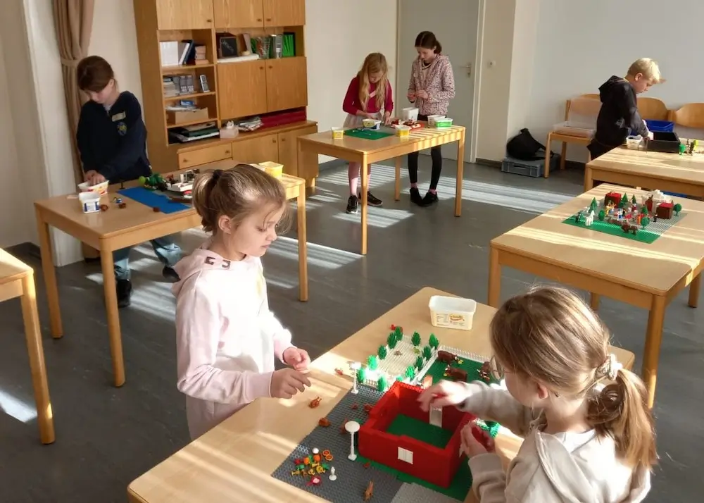 Kinder bauen an Tischen Lego-Szenen