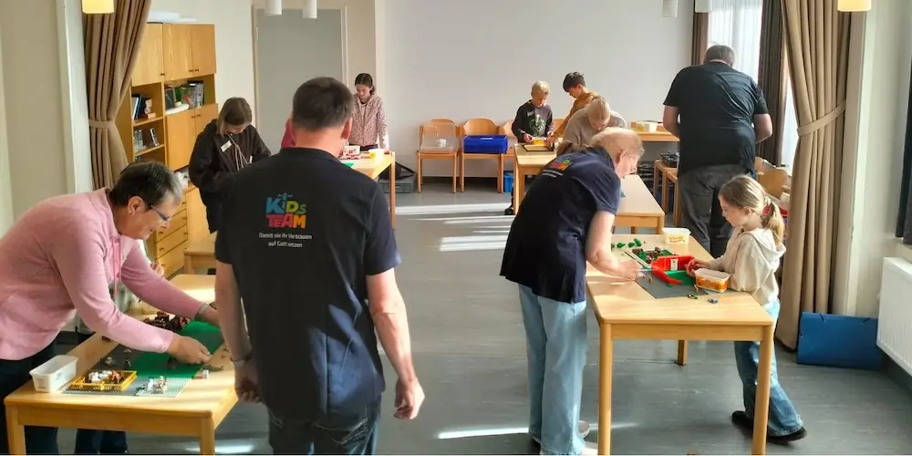 Mehrere Kinder bauen an Tischen verschiedene Lego-Szenen auf
