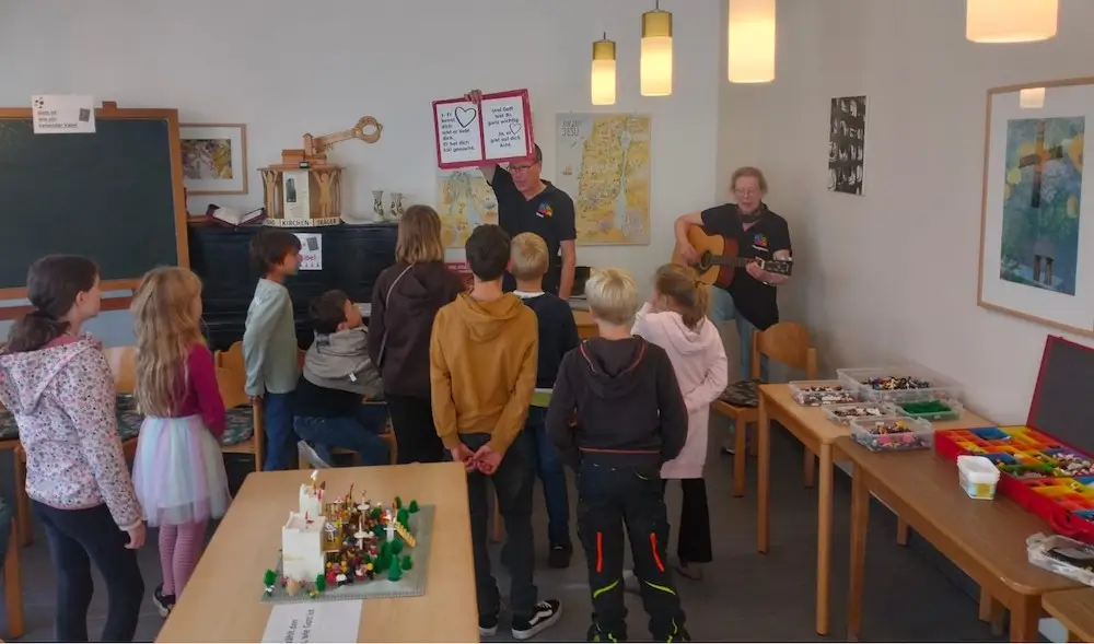Eine Gruppe Kinder singt mit Knut und Margarethe Ahlborn im Gemeindehaus der Johanneskirche